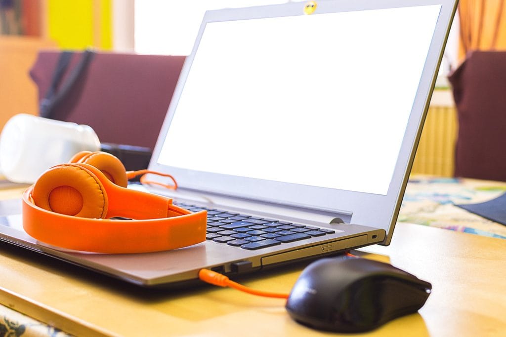 Laptop na biurku z pomarańczowymi słuchawkami